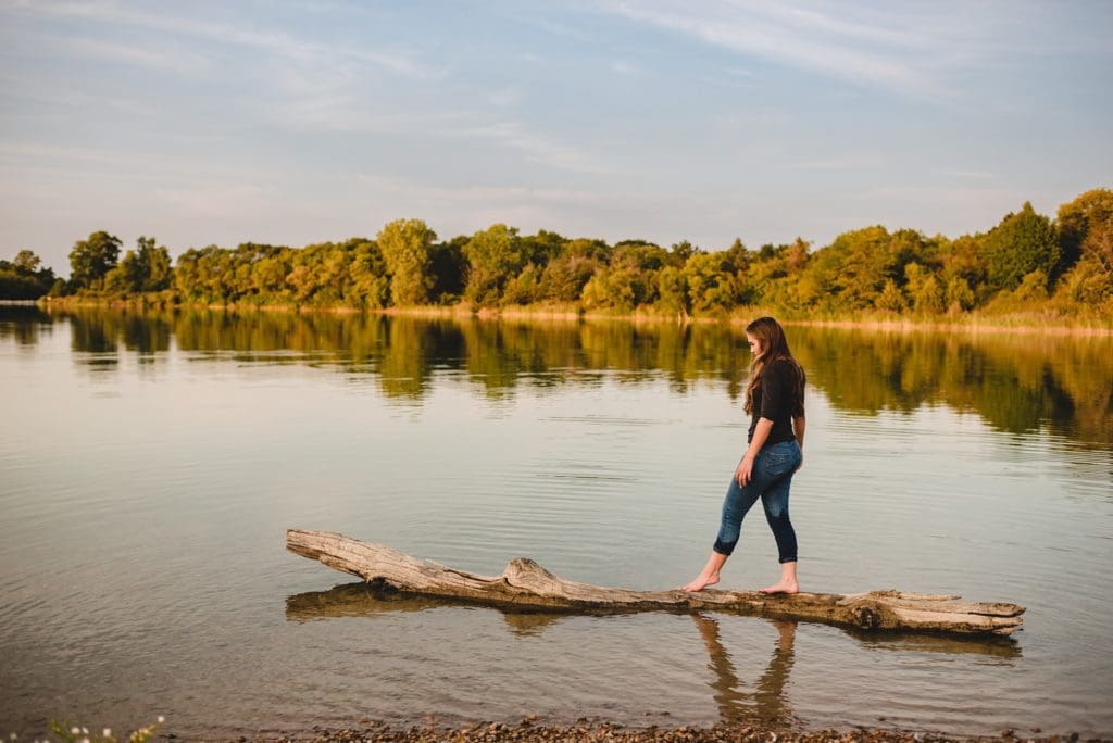 senior girl walking on a log in the lake