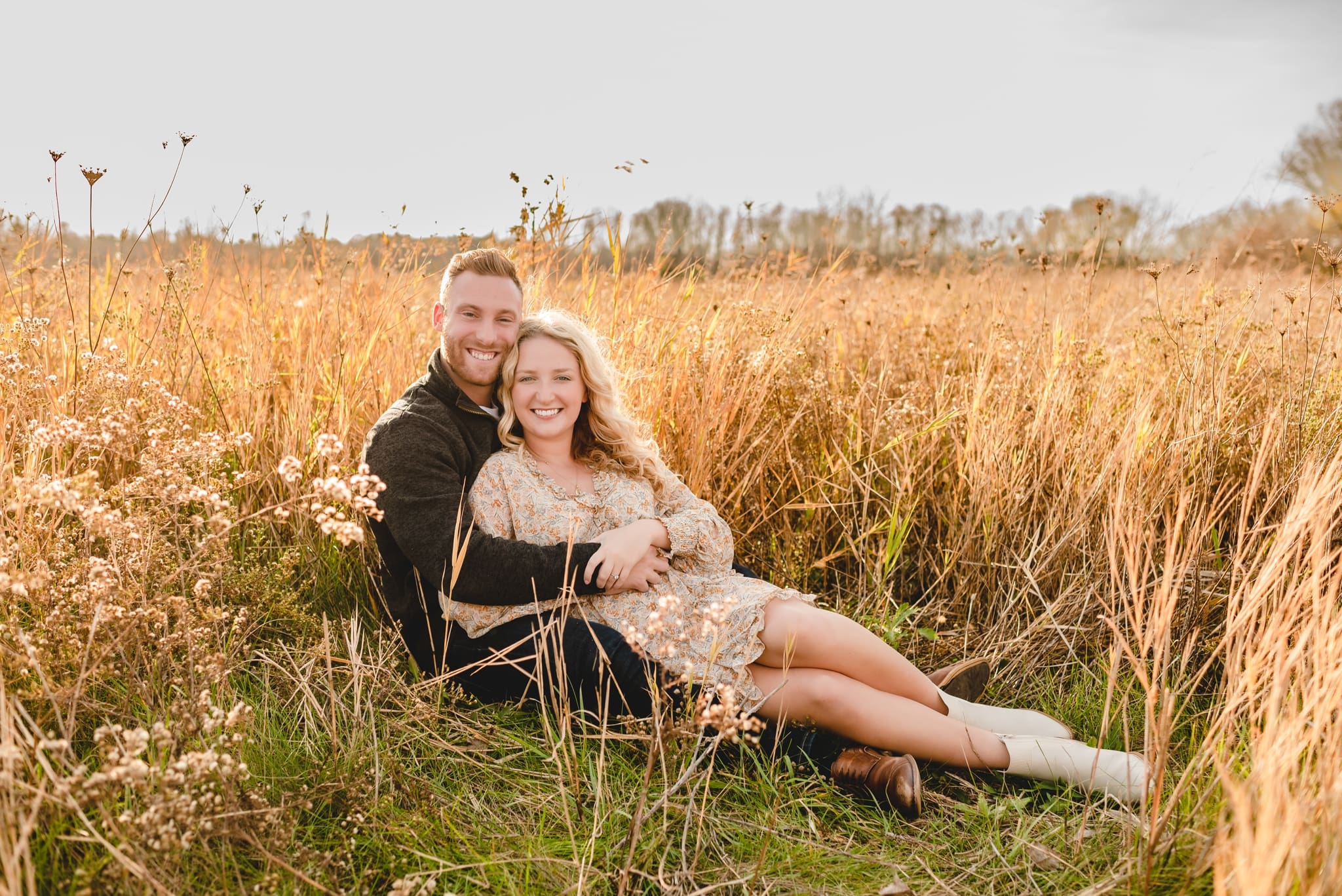 couple laying in golden tall grass for engagement session