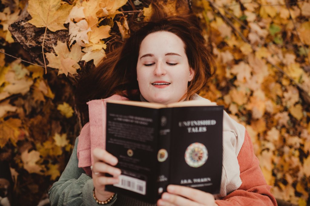woman reading book in fall leaves