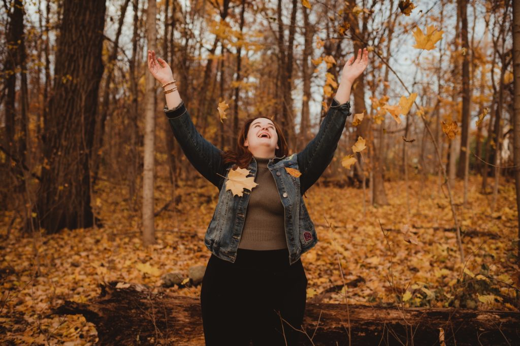 woman throwing up golden fall leaves