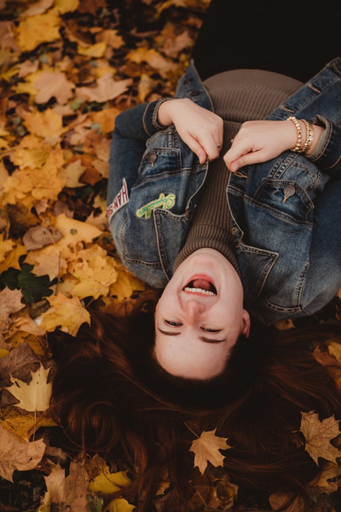 woman laying in fall foliage