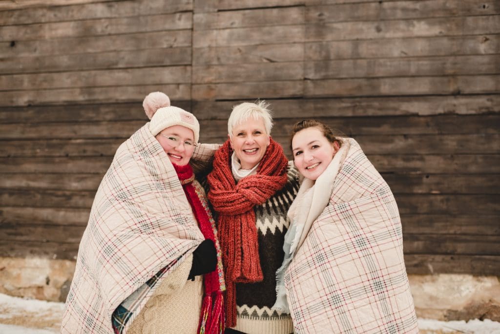 mom and daughers wrapped in plaid quilt for winter photo session