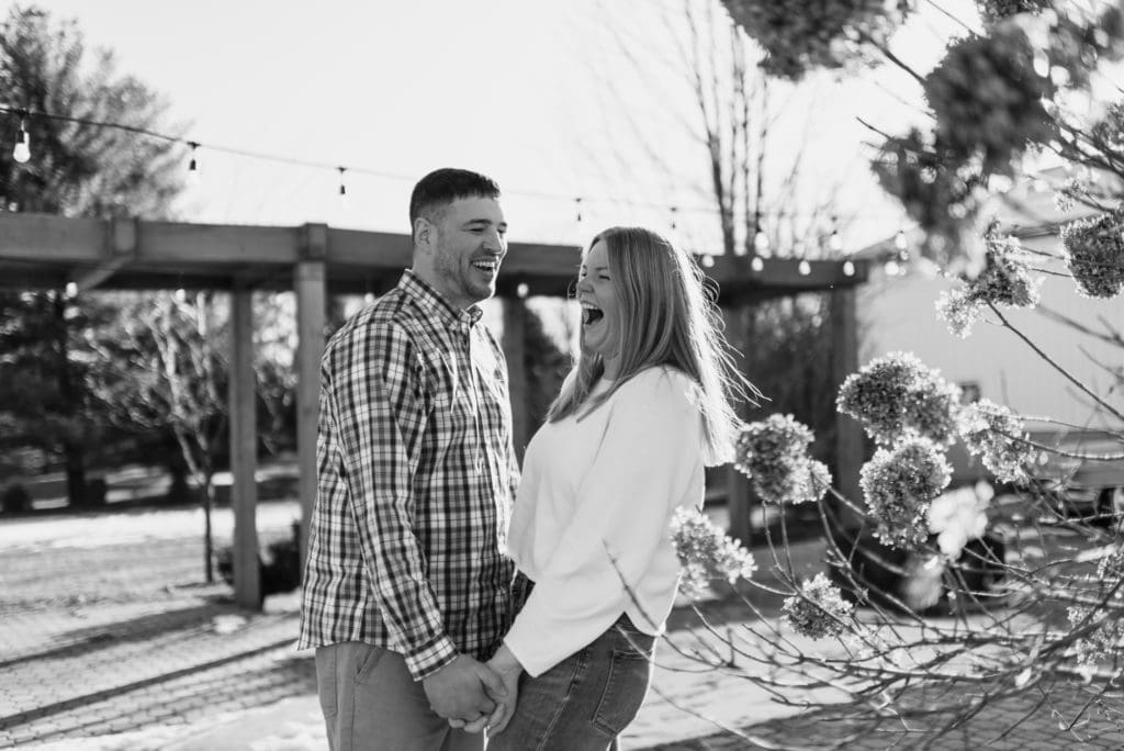 black and white image of couple laughing together during engagement session