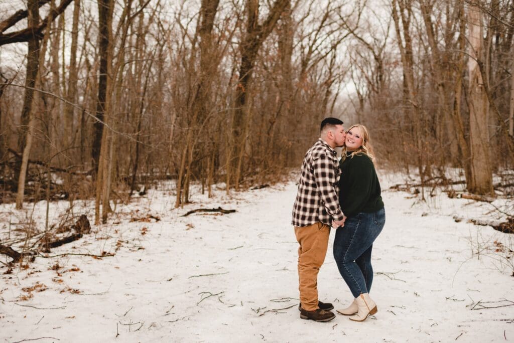man kissing his fiance as she looks at the camera