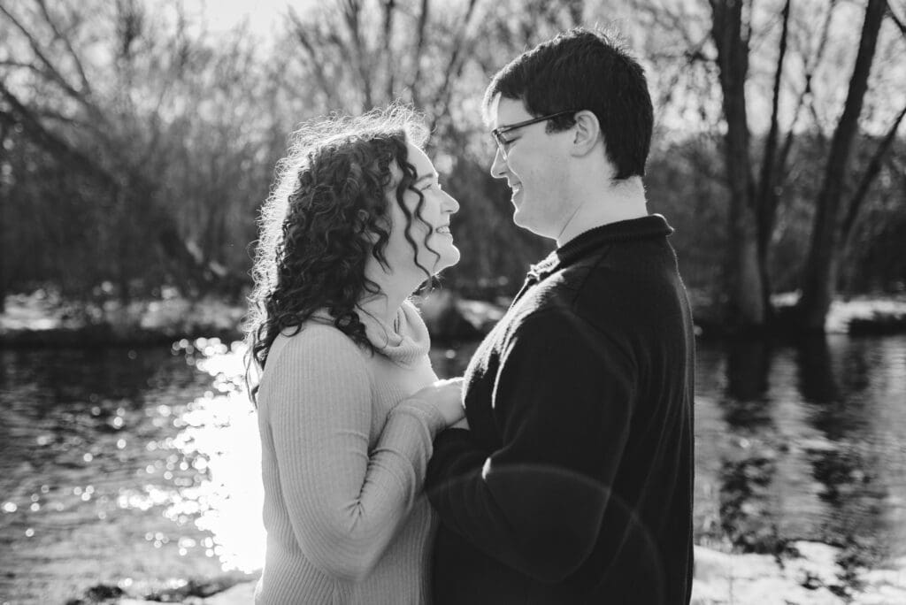 black and white engagement photo of backlit couple holding hands together
