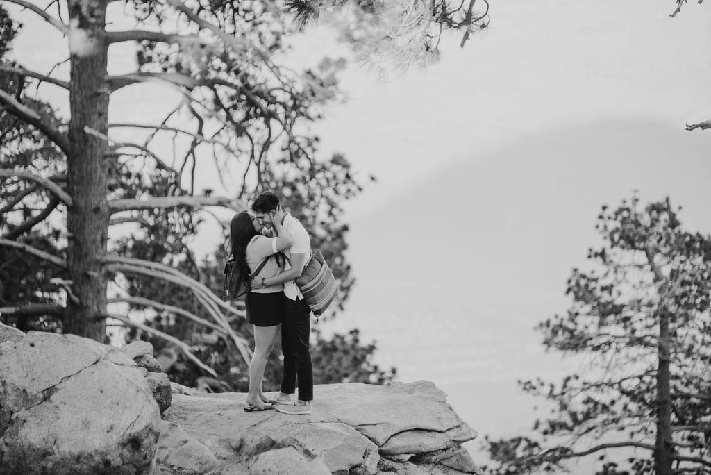 couple kissing on a rock with the palm springs valley behind them