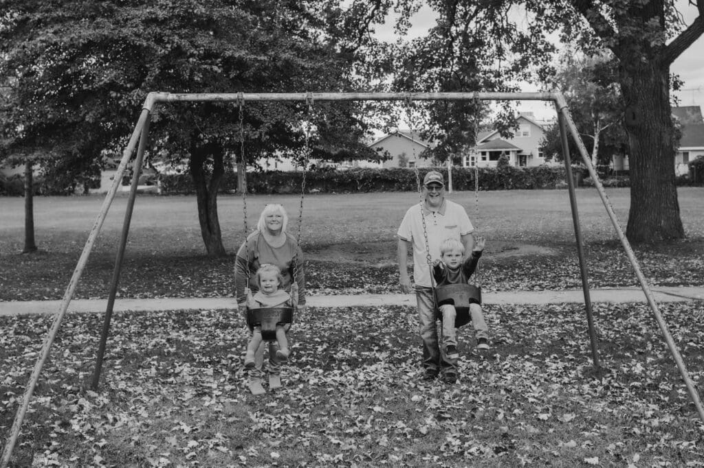grandparents pushing toddler grandchildren on swings at doty park in neenah wisconsin