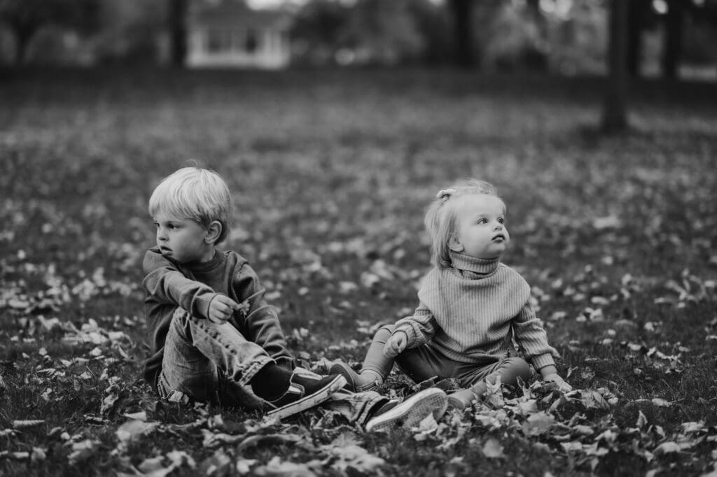 toddlers playing in fall leaves at the park