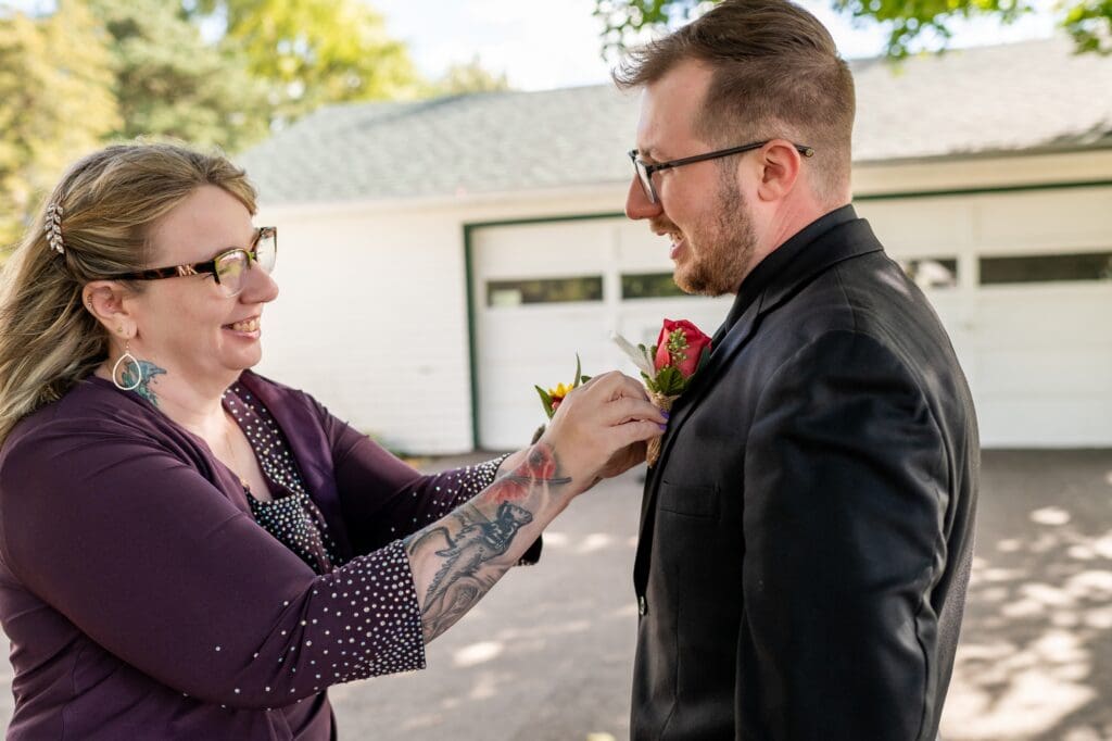 mother of the groom putting on his boutonniere 