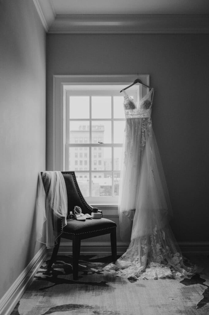 bridal details with dress hanging by the window